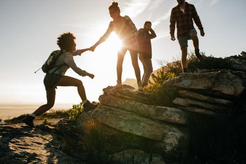 people helping others up a mountain